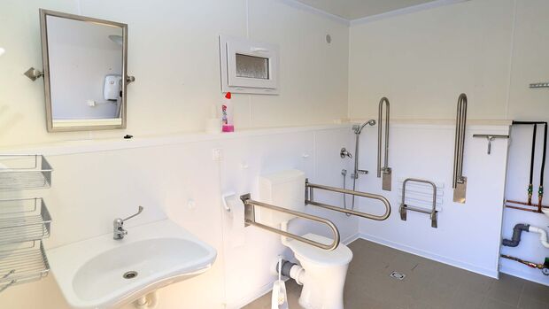 Behindertengergerechtes Badezimmer mit Waschbecken, Dusche und Toilette 