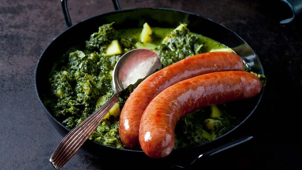Curly kale with potatoes and two minced pork sausages in pan