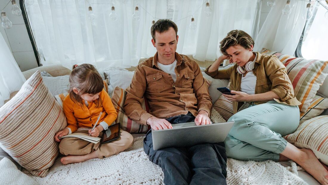 Father, mother and little daughter with gadgets sitting in the camper