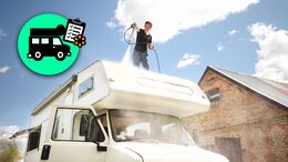 Man standing on campervan's roof cleaning it with pressure washer